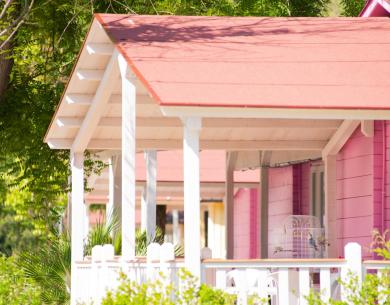 Cottage rosa con veranda e gabbia per uccelli.