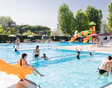 Piscine extérieure avec toboggans et personnes profitant du soleil.