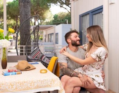 Couple souriant s'embrassant sur une véranda avec des fleurs et des jeux de société.