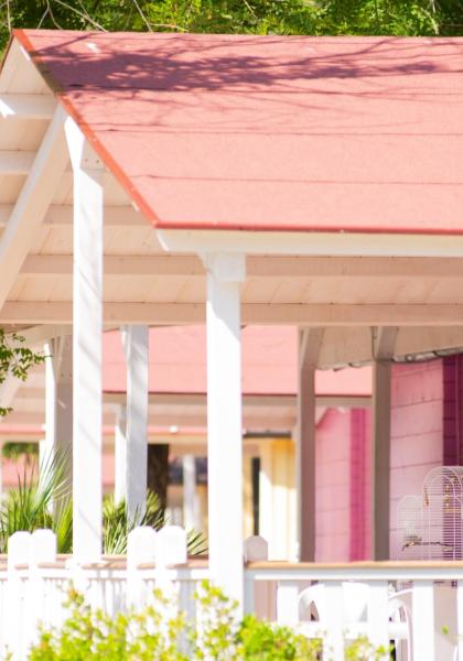 Pink cottage with porch and birdcage.