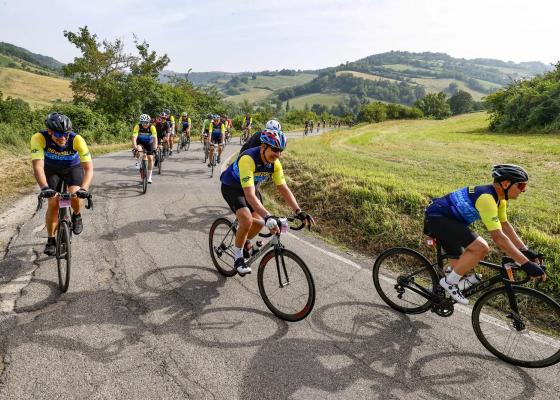 Ciclisti percorrono una strada panoramica in campagna.