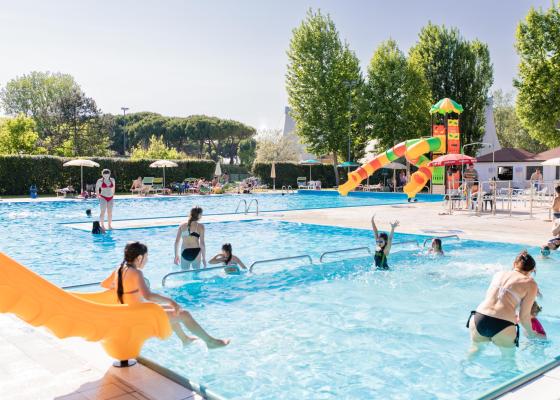 Piscine extérieure avec toboggans et personnes profitant du soleil.