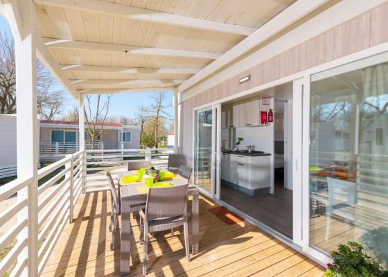 Terrasse avec table et cuisine moderne dans une maison mobile.