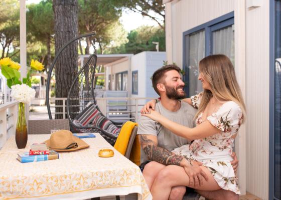 Couple souriant s'embrassant sur une véranda avec des fleurs et des jeux de société.